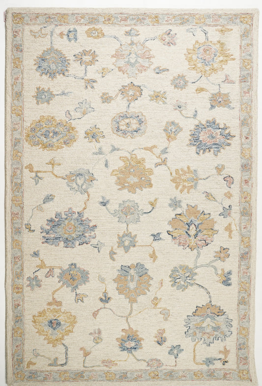 Puṣpāstaraṇa cream wool rug with ochre and blue floral vines and a narrow botanical border.